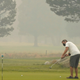 A golfer wears a face mask as he practices his putting at the smoke shrouded Lake Tahoe Golf Course in South Lake Tahoe, California.
